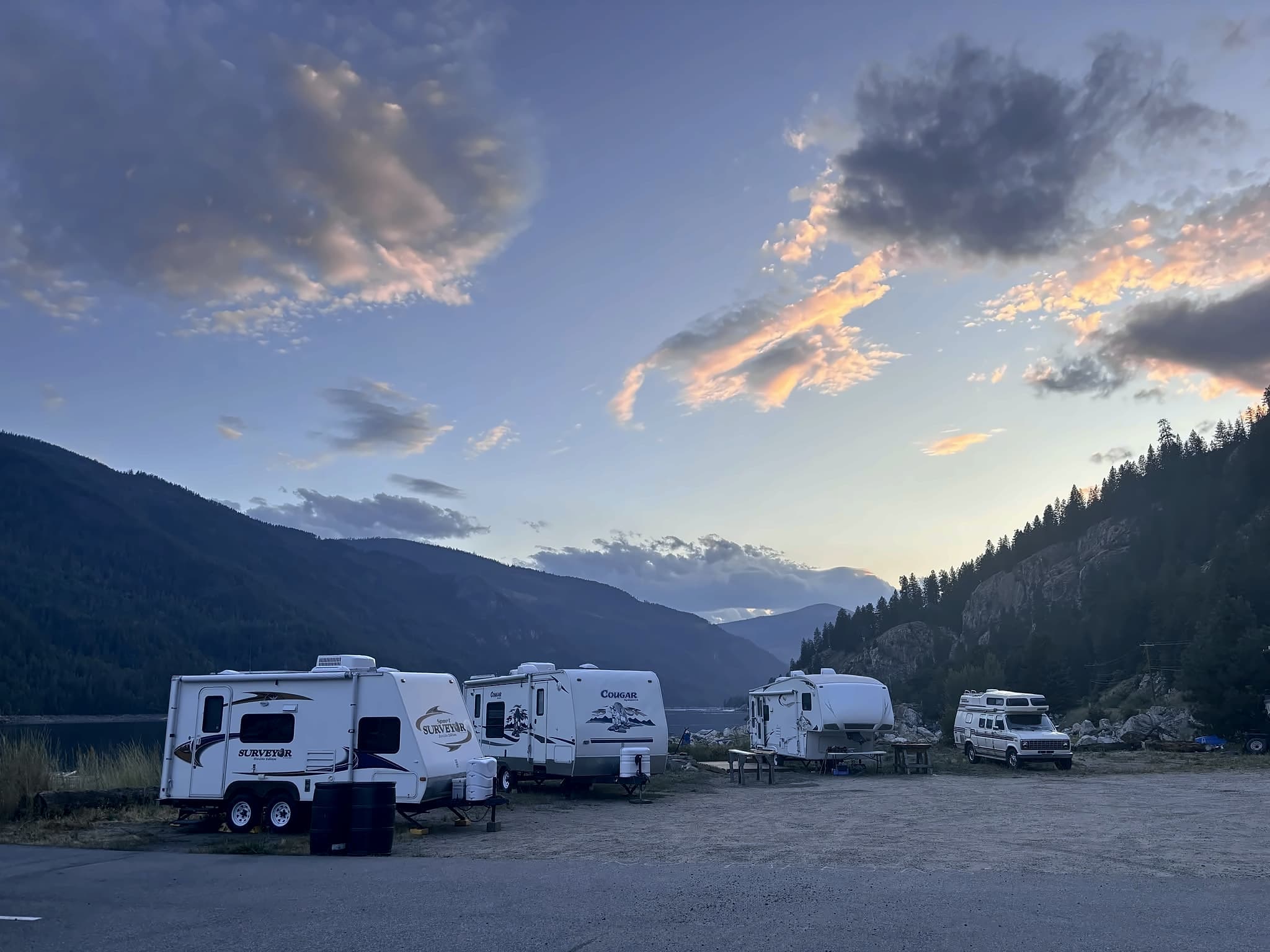 Trailers parked in a row at the Scotties Marina campsites, with the lake and the mountains behind them.