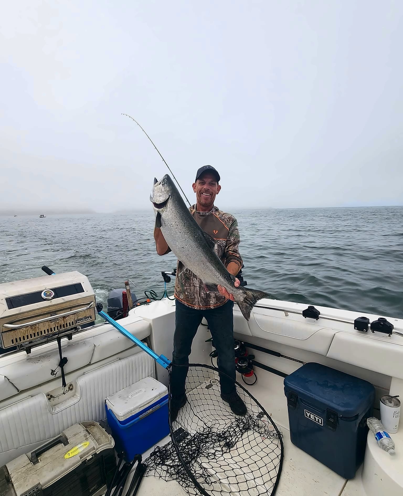 Dave standing in a boat, holding up a big fish.